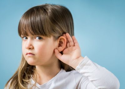 Child with hearing problem on blue background. Hearing loss in childhood, symptoms and treatment concept. Close up, copy space.